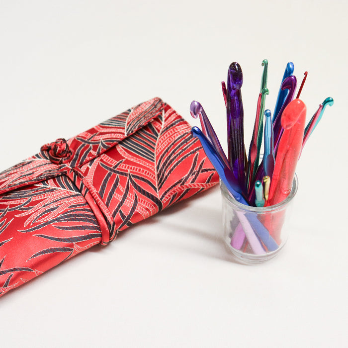 hiyahiya aluminium and acrylic crochet hooks displayed in a glass jar next to a Chinese brocade style wrap case.