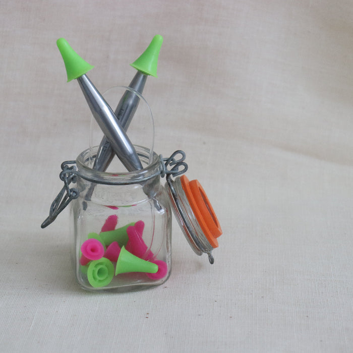 pink and green hiyahiya point protectors on some metal hiyahiya circular knitting needles.