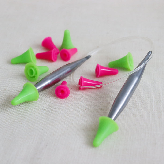 pink and green hiyahiya point protectors on some metal hiyahiya circular knitting needles.