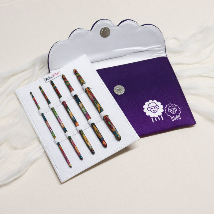 Knitpro symfonie multicoloured layered wood crochet hooks in white sleeve with elastic loops with a purple cloth case.